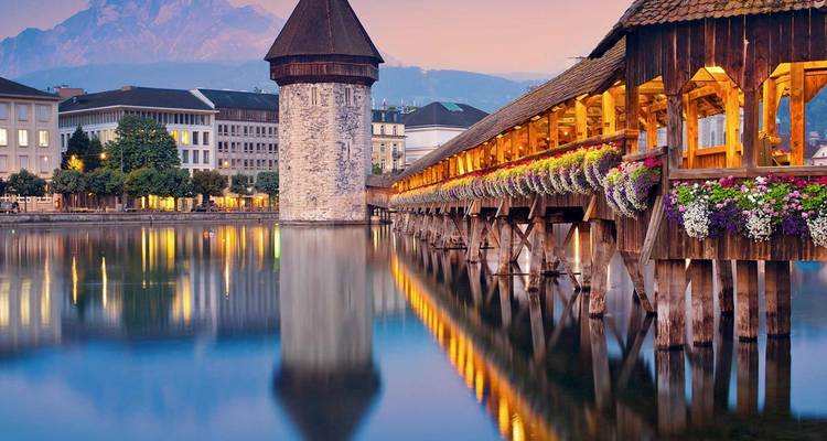 Luzerns historische Kapellbrücke und der Turm erstrahlen über den spiegelnden Abendgewässern.