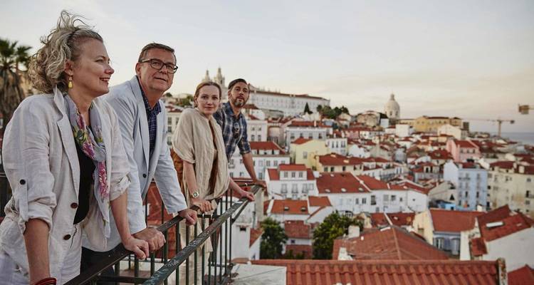 Groupe de touristes contemplant le paysage urbain avec des bâtiments traditionnels à Lisbonne.