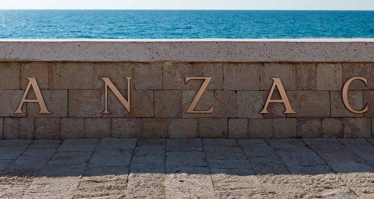 Mur commémoratif en pierre à ANZAC Cove avec la mer bleue qui s'étend au-delà