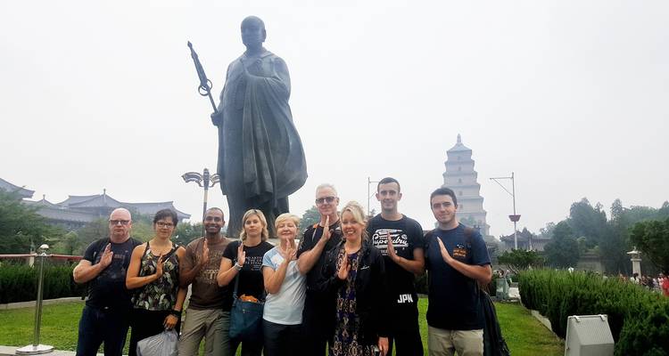 Touristen, die vor einer großen Statue und einer Pagode posieren.