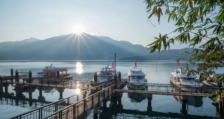 Des bateaux amarrés sur un lac serein au lever du soleil.