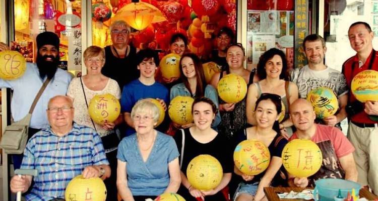 A group of people holding lanterns in front of a decorated shop.