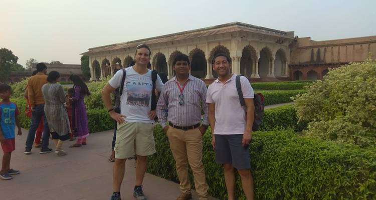 Groupe d'hommes posant devant un jardin et un bâtiment historique.