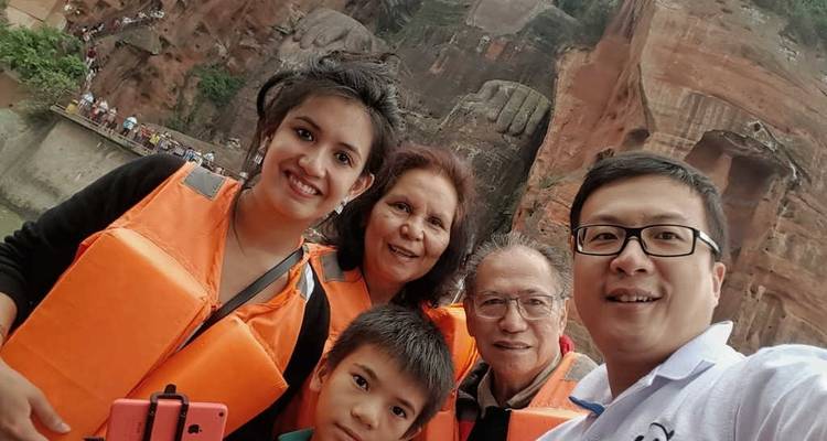 Family wearing life vests posing on a boat with rock formations.