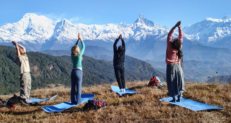 Gruppe beim Yoga mit Bergen im Hintergrund an einem klaren Tag.
