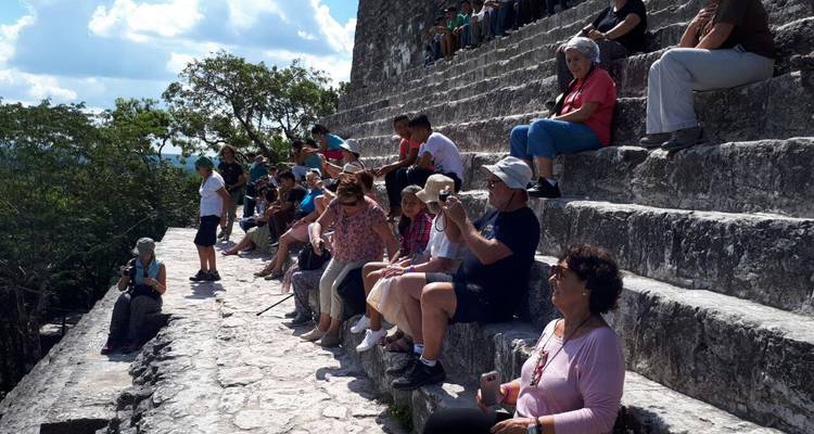 Een groep toeristen zit op oude stenen trappen.