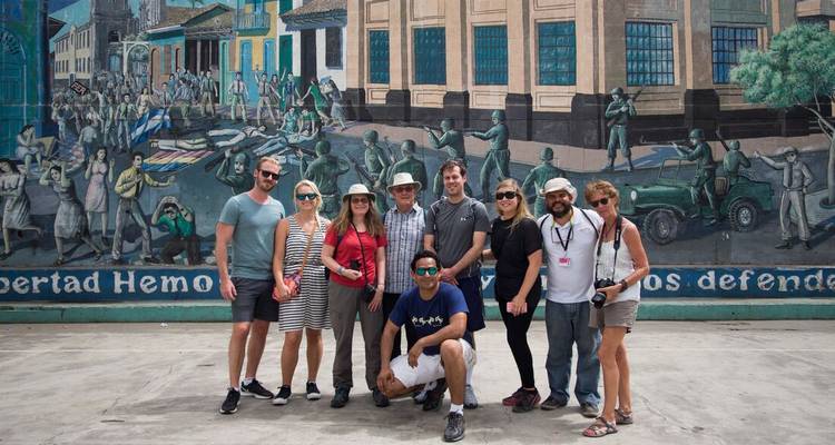 Un groupe de personnes posant devant une fresque murale dans la rue.