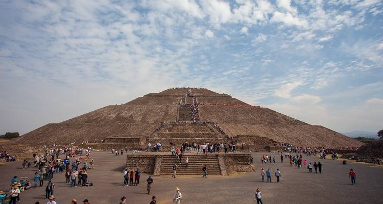 Une grande pyramide de pierre avec de nombreuses personnes qui l'escaladent et l'entourent.