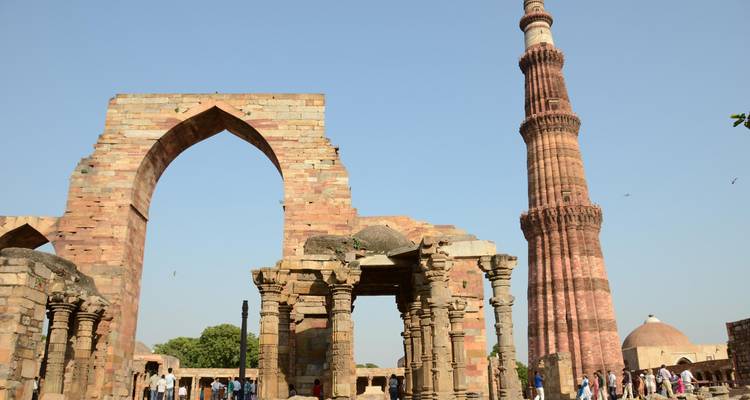 Qutub Minar avec les ruines environnantes et les visiteurs.
