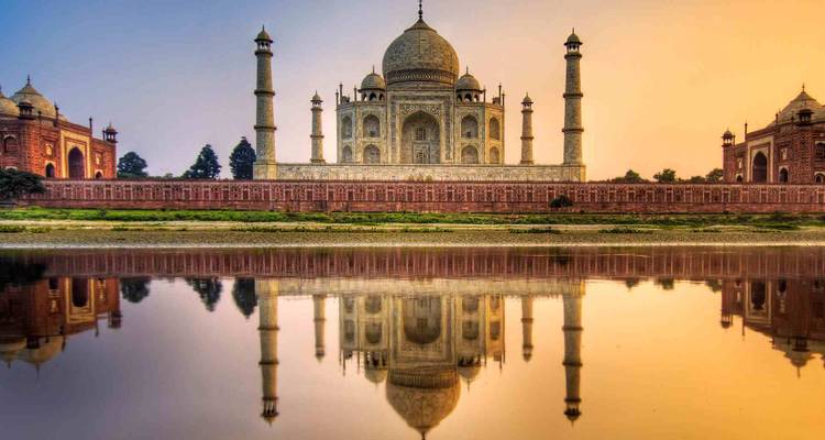 Taj Mahal se reflétant dans une rivière au coucher du soleil.