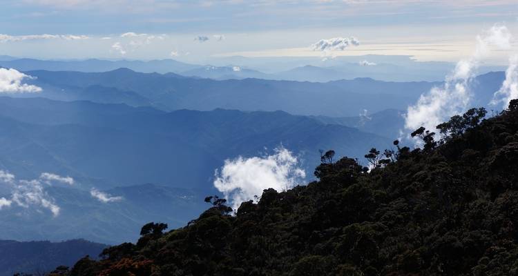 Met wolken bedekte bergketens onder een heldere hemel.