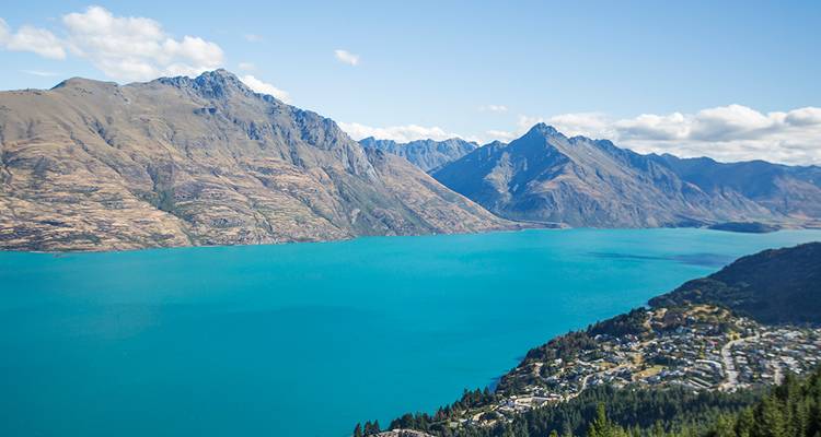Lago Wakatipu de un turquesa brillante bordeado por una cadena montañosa irregular bajo un cielo despejado.