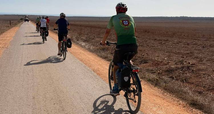 Grupo de ciclistas en una carretera a través de un paisaje árido durante el día.