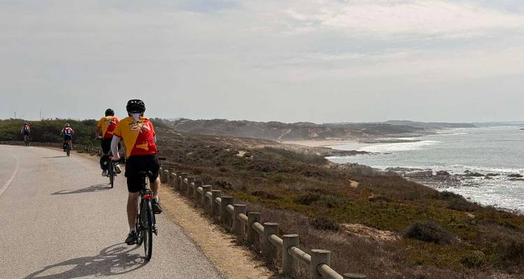 Ciclistas recorriendo una carretera costera con vistas al océano.