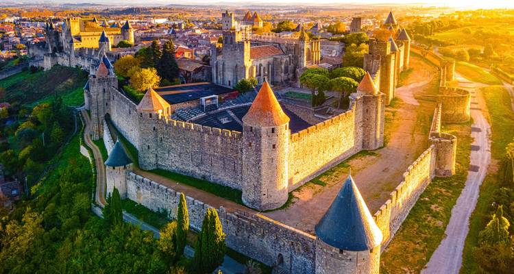 Vue aérienne d'une ville médiévale fortifiée au coucher du soleil.