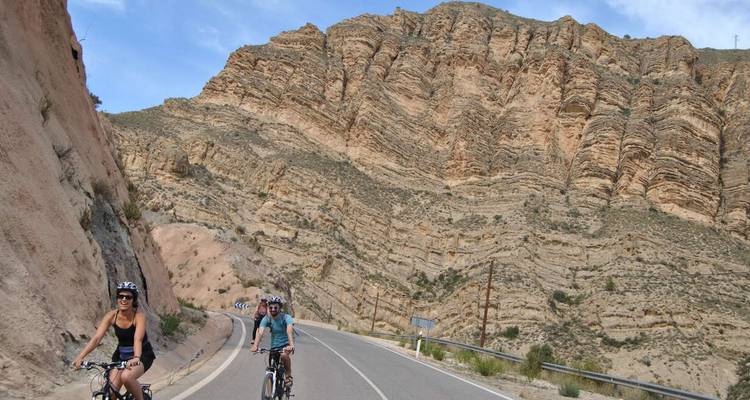 Des personnes faisant du vélo sur une route avec des collines rocheuses en arrière-plan.