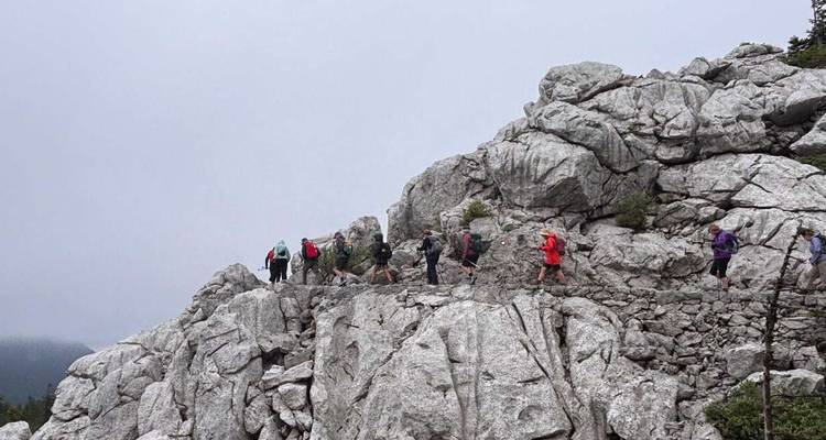 Group hiking along a rocky ridge in a cloudy weather.