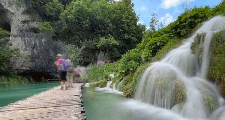 Person walking on a bridge by a waterfall, slightly blurry.