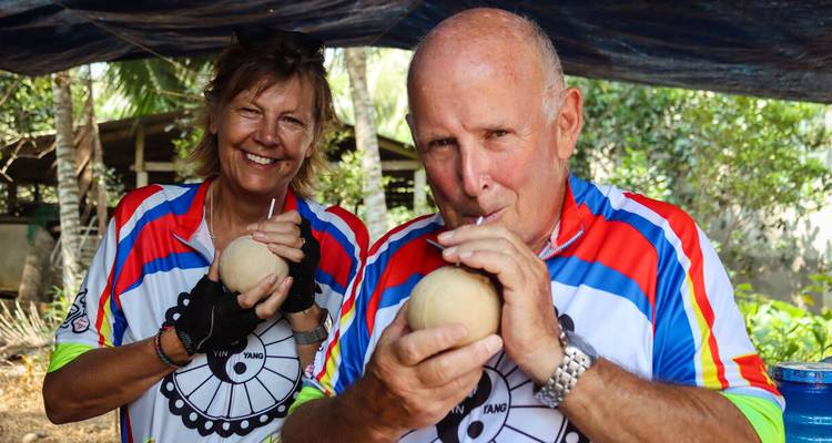 Couple drinking coconut water while wearing cycling jerseys.