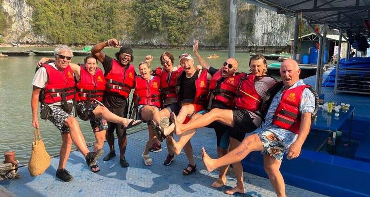 Group of people in life vests posing with excitement on a boat.