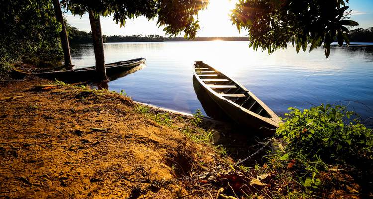 Vue du coucher de soleil sur des canoës au bord d'un lac serein.