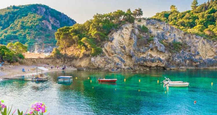 Baie d'émeraude cristalline entourée de falaises rocheuses et de forêts luxuriantes avec de petits bateaux amarrés près d'une plage de sable.