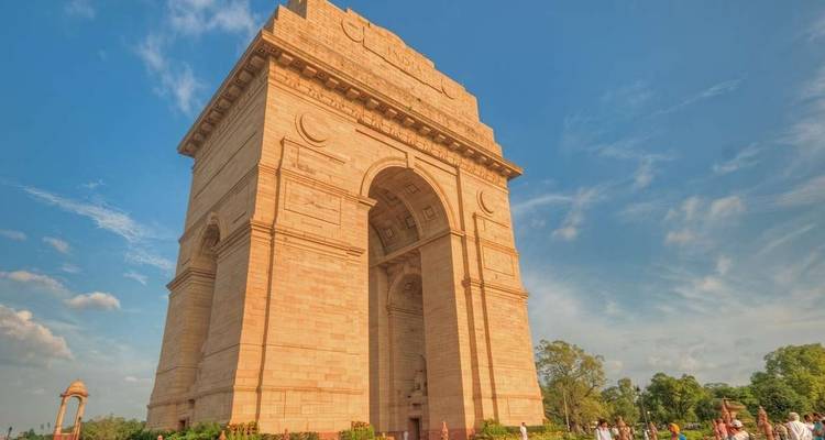A large arch monument with people walking around on a sunny day.
