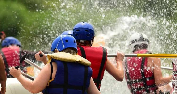 Balseros cargados de adrenalina con cascos coloridos avanzan con fuerza a través de aguas bravas espumosas mientras el agua salpica por todos lados.