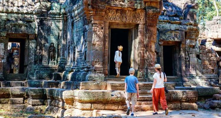 Les visiteurs explorent l'entrée en pierre ornementée d'un ancien temple de la jungle entouré de statues sculptées.