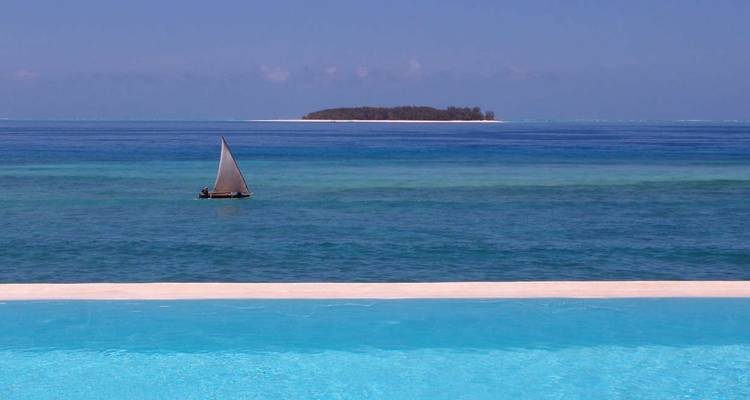 Dhau segelt auf den blauen Gewässern mit Blick auf eine entfernte Insel.