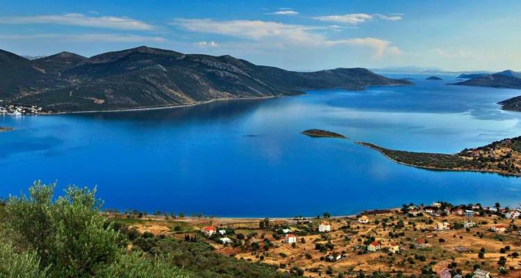Vue panoramique sur le golfe bleu profond entouré de collines escarpées et de maisons rurales dispersées sur l'île d'Eubée, Grèce.