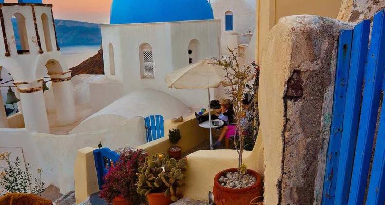 Église classique aux dômes bleus, murs blanchis à la chaux et couleurs du coucher de soleil égéen à Oia, Santorin.