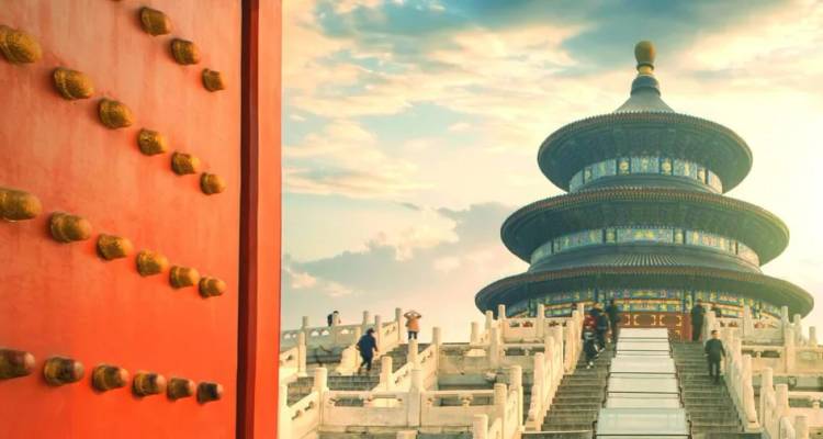 Tempel van de Hemel in Beijing met toeristen op de trap en een levendige rode paleisdeur op de voorgrond.