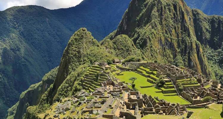 Iconisch uitzicht op de ruïnes van Machu Picchu op een plek tussen weelderige Andespico's.