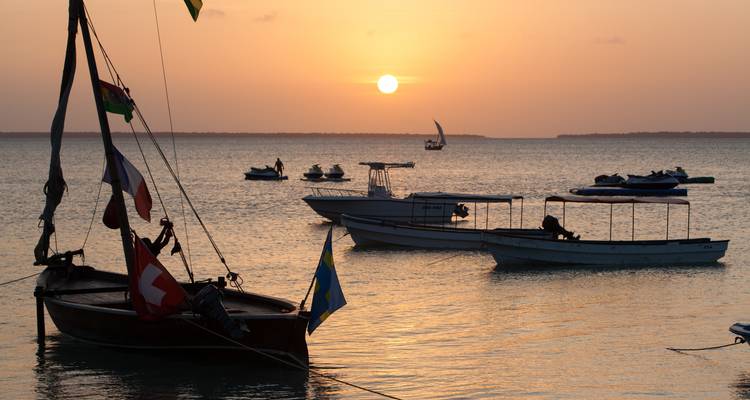 Barcos en el agua con una puesta de sol vibrante en el fondo.