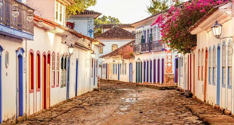 Rue pavée de charme bordée de maisons coloniales aux couleurs pastel et de bougainvillées à Paraty, Brésil.