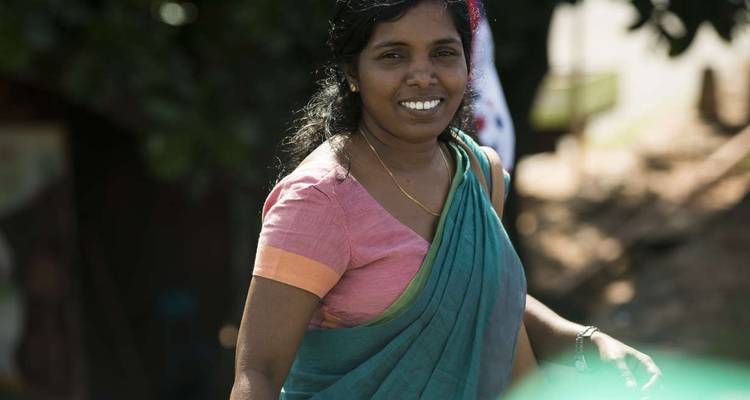 Smiling woman wearing a sari walking outdoors.
