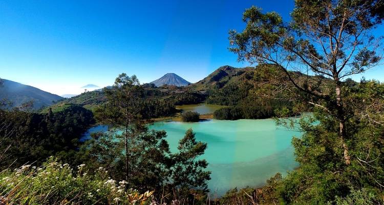 Scenic view of a turquoise lake surrounded by mountains with clear skies.