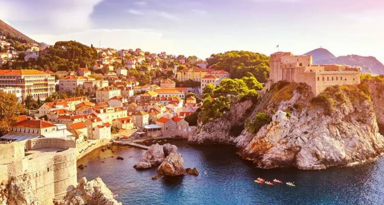 Gouden laat-middaglicht baadt Dubrovniks ommurede oude stad en rotsachtige kustlijn aan de Adriatische Zee.