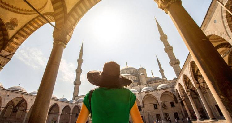 Femme sous des arches dans une mosquée avec un arrière-plan architectural.