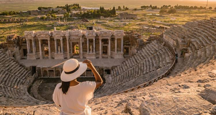 Femme observant un amphithéâtre antique au coucher du soleil.