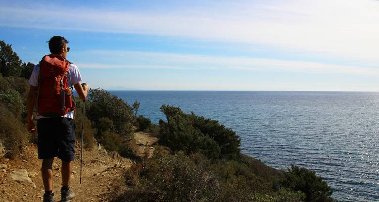 Personne faisant de la randonnée le long d'un sentier côtier avec vue sur l'océan.