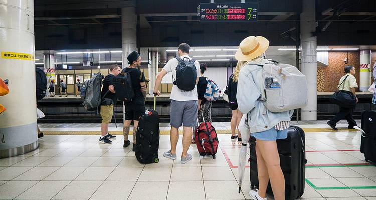 Viajeros esperando en el andén de una estación de tren con su equipaje.