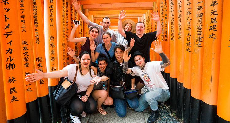 Grupo de personas posando alegremente delante de las tradicionales puertas naranjas.