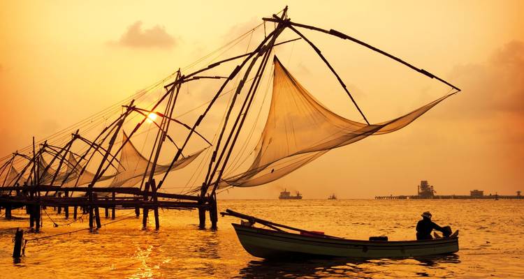 Redes de pesca silueteadas contra una puesta de sol sobre el agua.