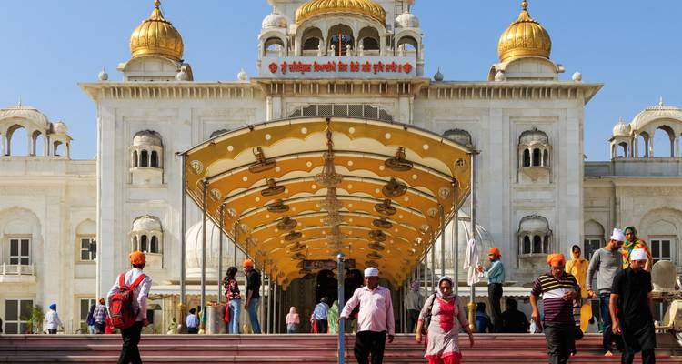 Visitantes entrando en un gran templo con cúpulas doradas.