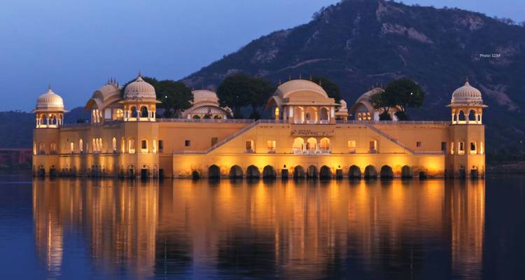 A well-lit water palace at night with reflections in the lake.