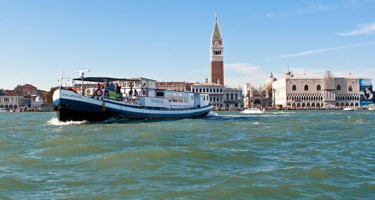 Barco navegando en el agua con vista de un paisaje urbano y una torre.
