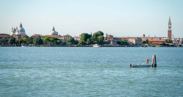 Una vista serena de Venecia con un barco y lugares emblemáticos.