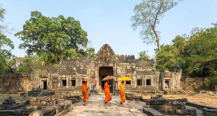 Moines bouddhistes marchant devant un temple ancien.